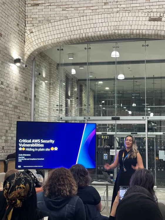 Zulia speaking to an audience beside a screen titled Critical AWS Security Vulnerabilities